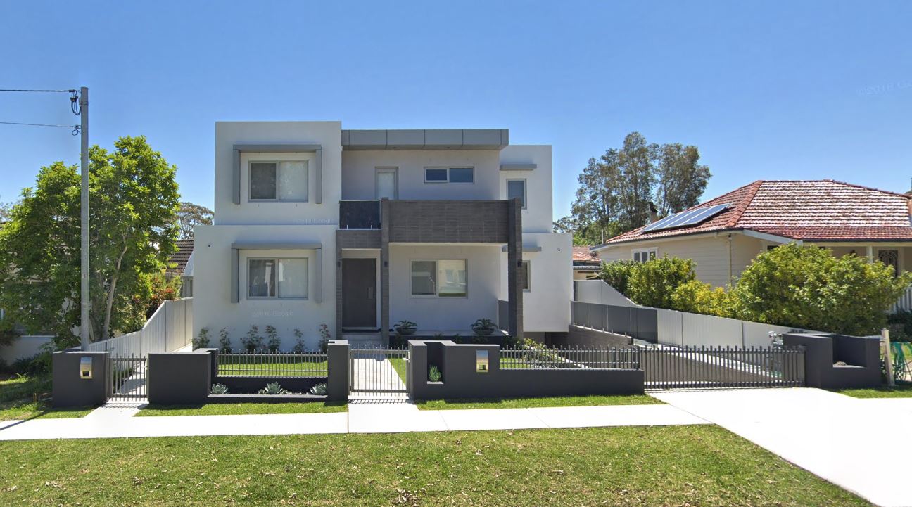 Completed two storey rendered new dwelling in Caringbah with dark feature cladding, timber front door and low front fence